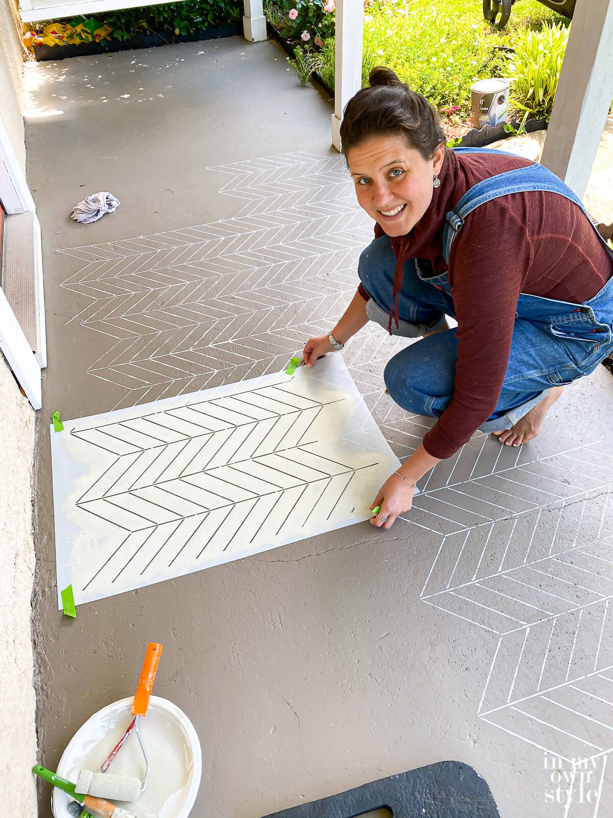 Lining up herringbone pattern stencil on porch floor and then taping it down.
