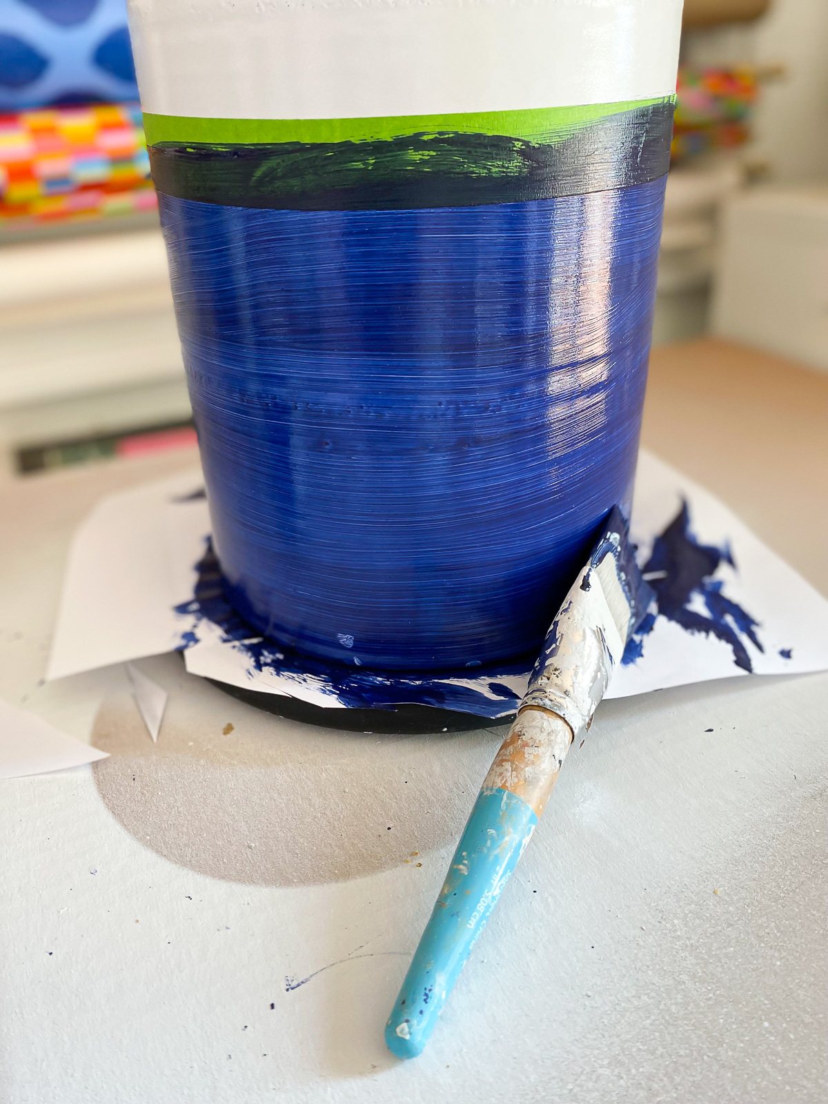 Brush on blue paint being applied to lamp base using a lazy Susan.