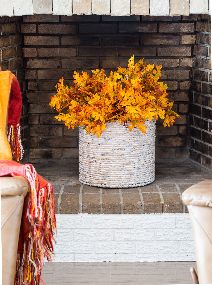 Fall leaves in basket placed in an unused fireplace.