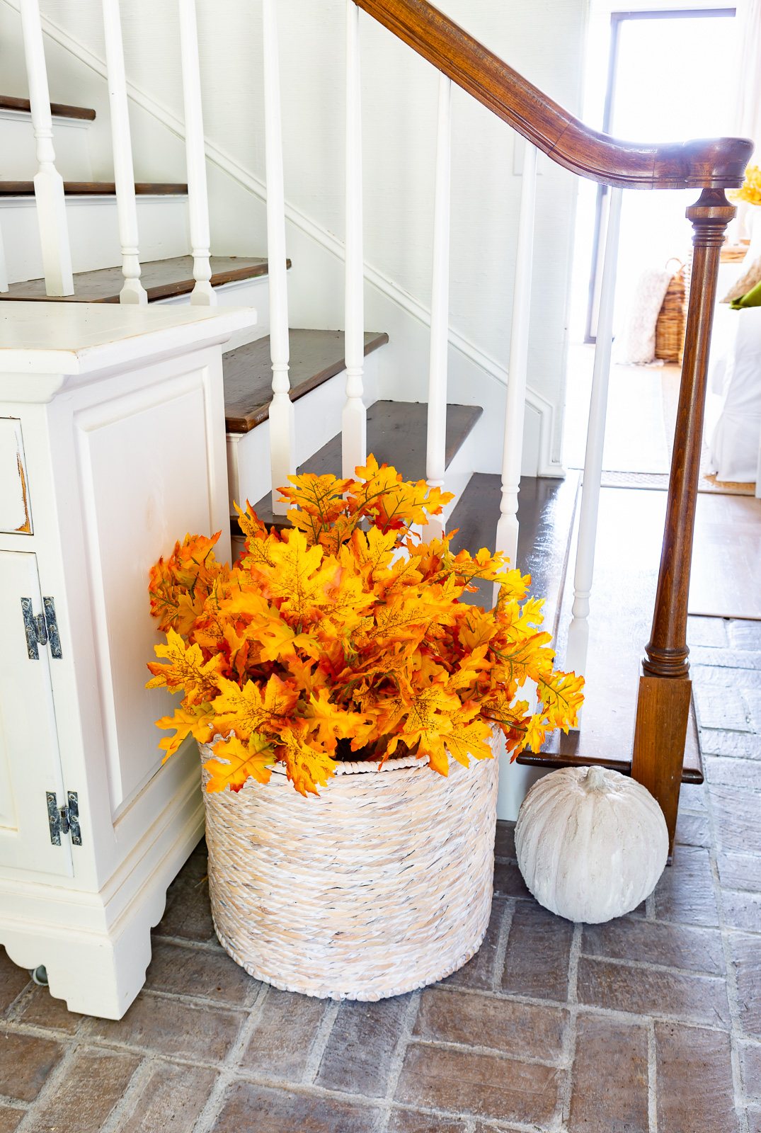 Round basket filled with faux Maple leaf branches.