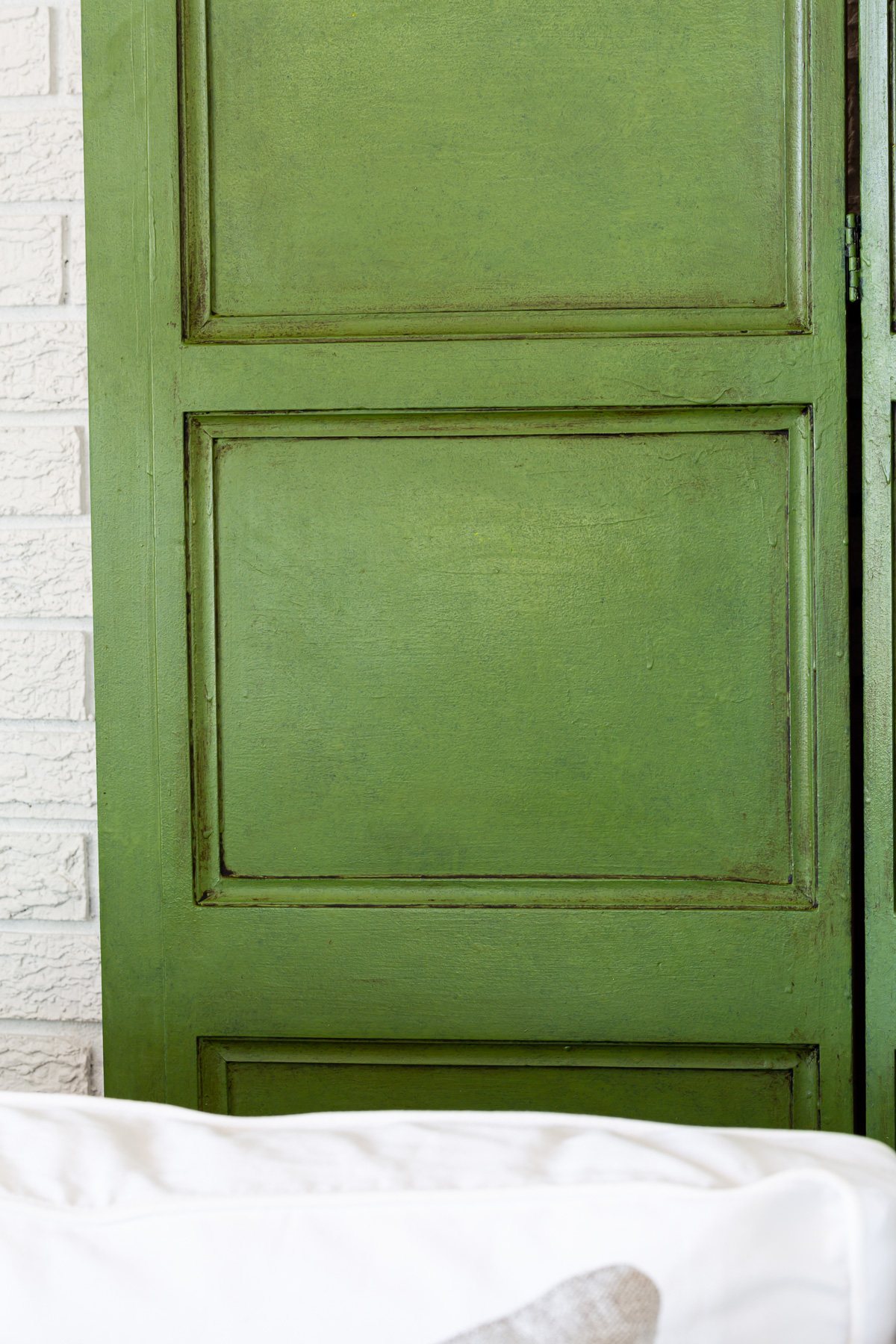 Close up photo of a green paint and glazed wood screen.