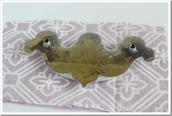 How to transform a drawer pull with a napkin. Pull is laying face down on back side of napkin.