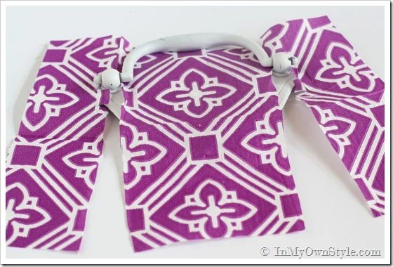Furniture drawer pulls getting covered in a purple and white paper napkin.
