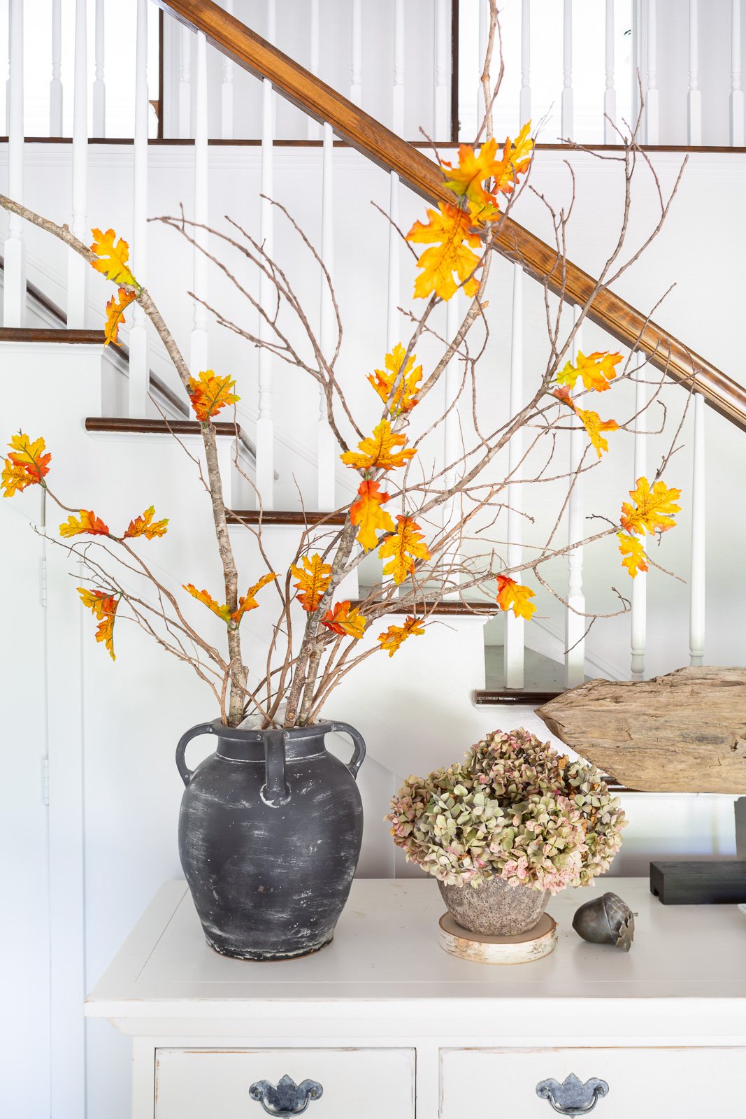 Single faux fall leaves added to real tree branches to decorate a home for fall.
