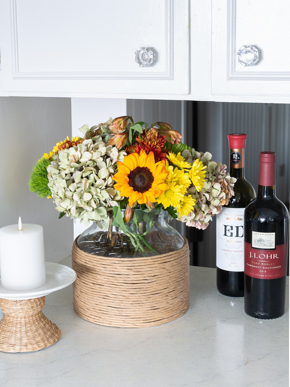 paper twist ribbon cord wrapped glass vase with fall flowers in it on a kitchen counter