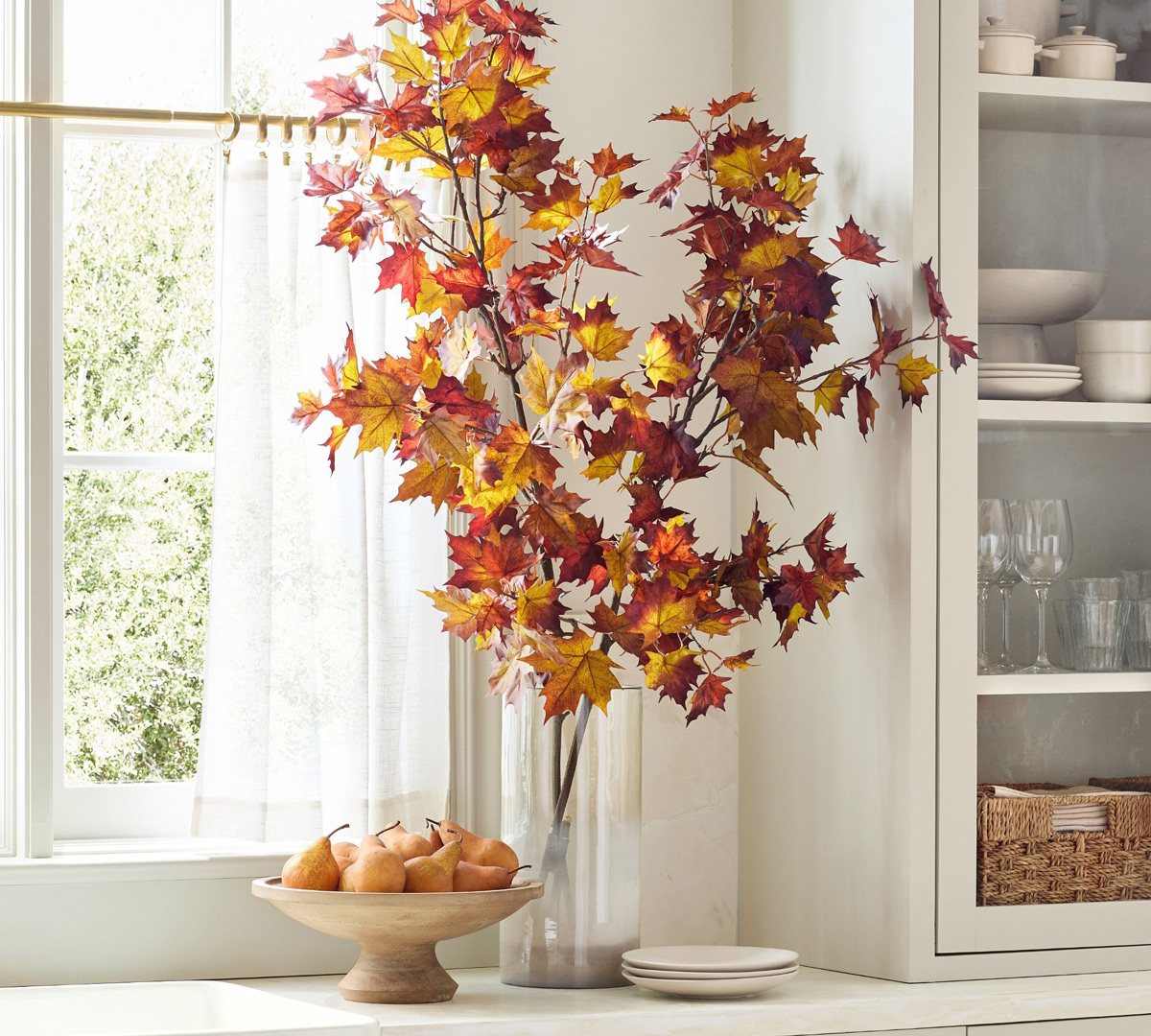 faux branches in glass vase on kitchen counter