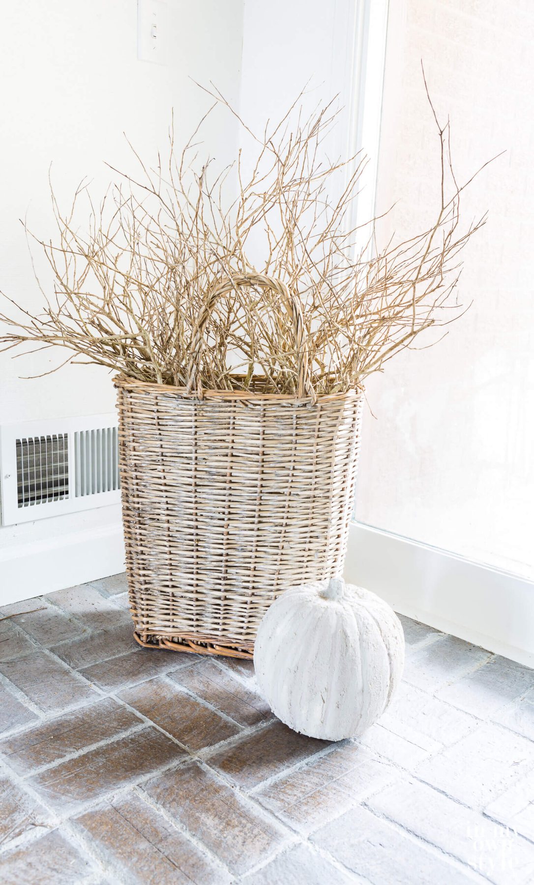 Tall handled basket with stone pumpkin in front of it.