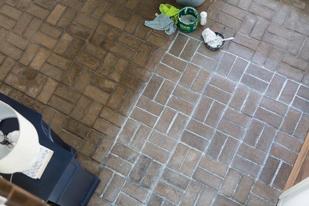 Photo taken from above looking down on the process of whitewashing the brick floor.
