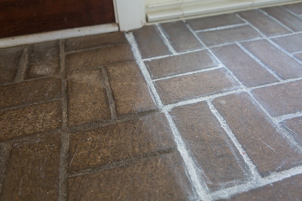 Close-up photo showing the before and after of the brick floor side by side with grout paint and without.