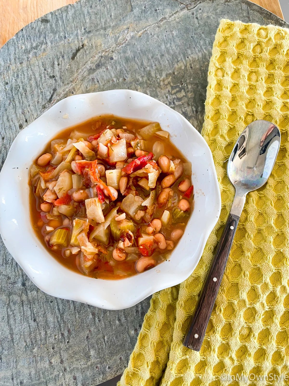 A bowl full of Ikarian stew with a napkin and spoon on the side.