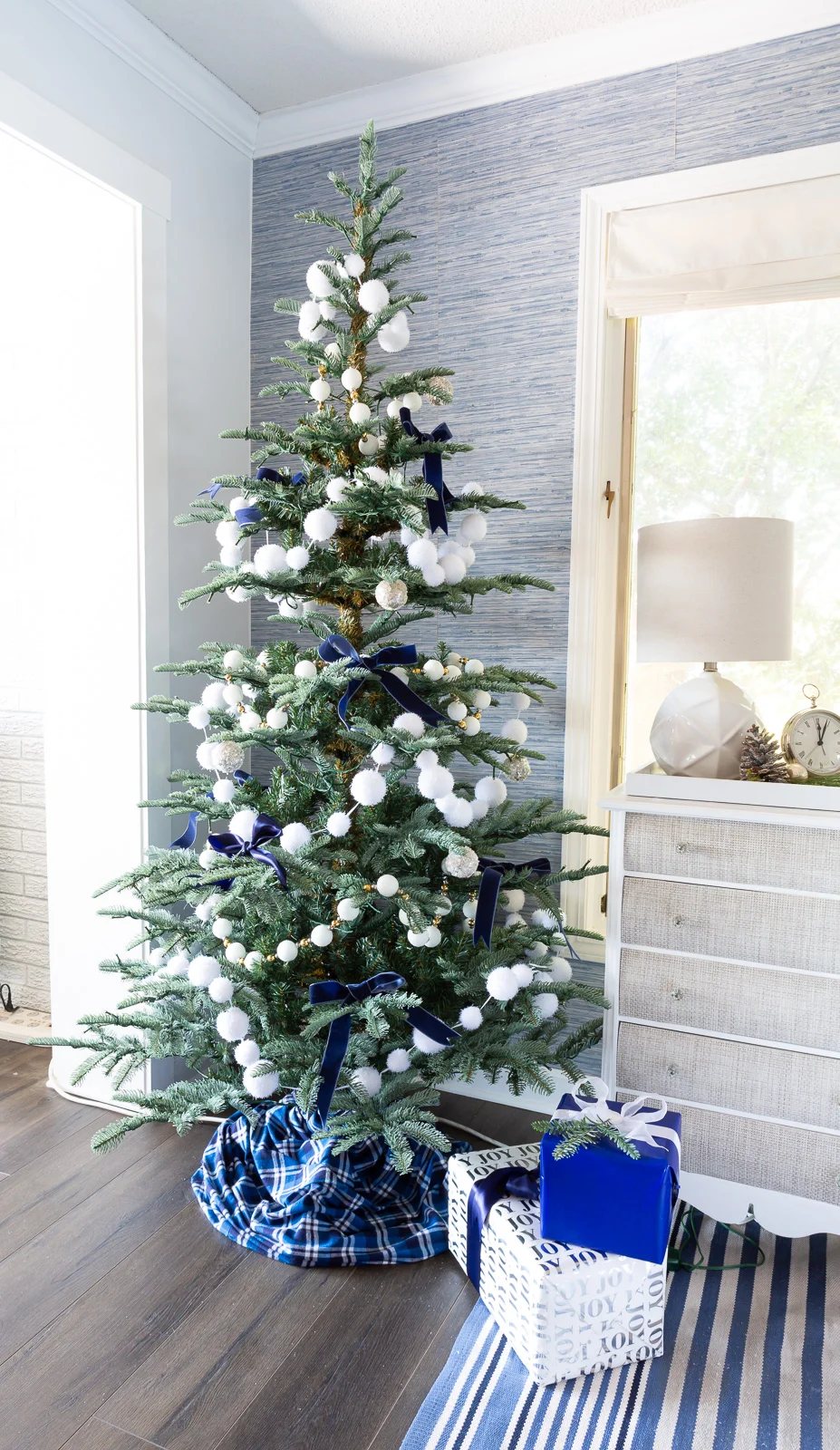 7' King Noble Fir Artificial Christmas Tree with 500 Warm White LED Lights decorated with white snowball garland and blue ribbon bows.