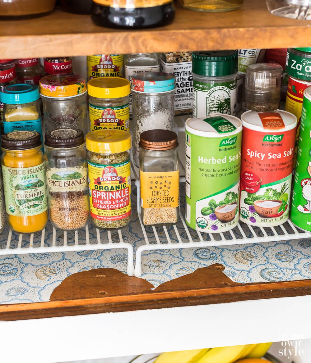 Before image showing spice cabinet with old ripped adhesive shelf lining paper.