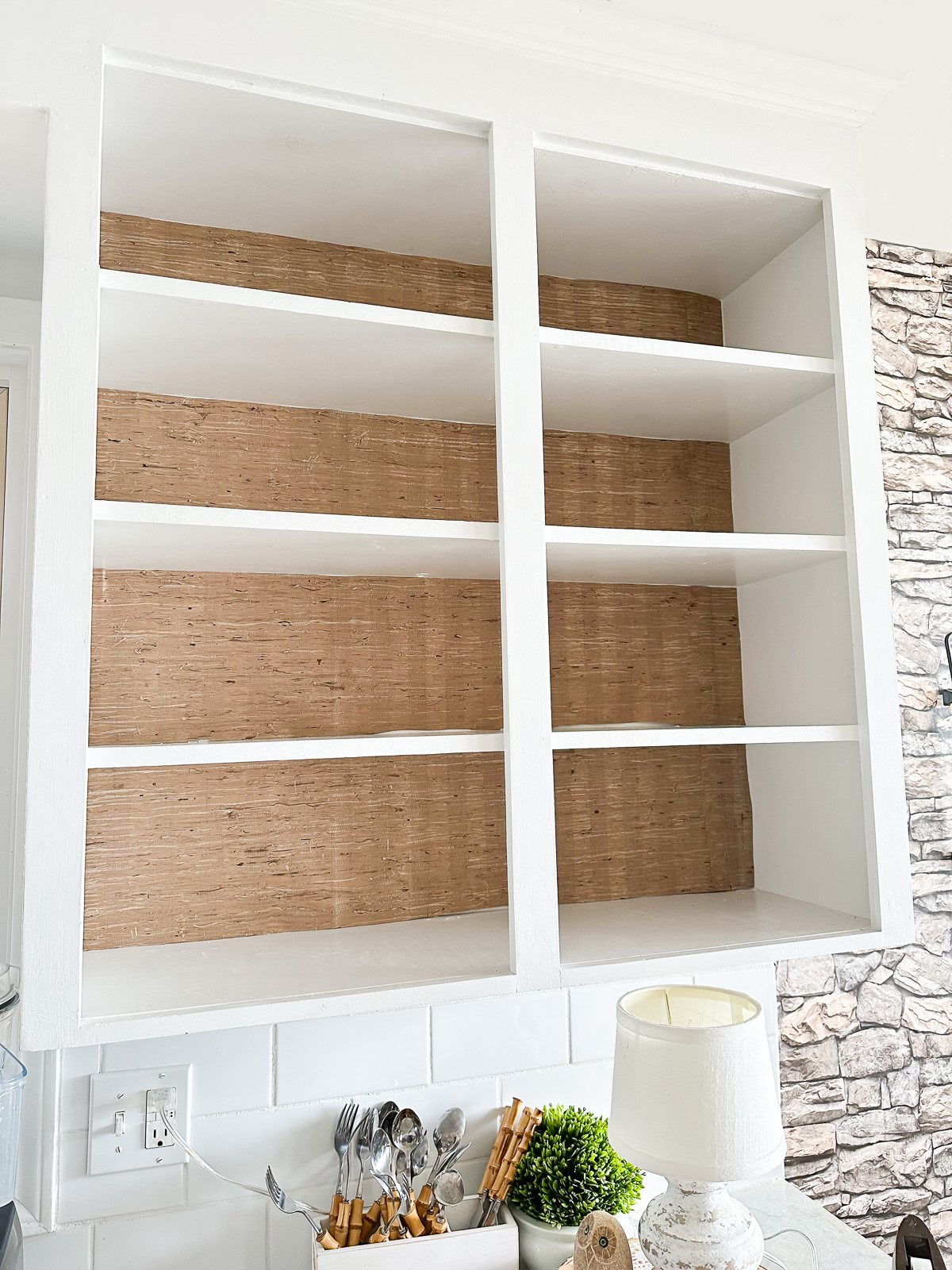 Grasscloth wallpaper added to the backs of open shelves in a kitchen to decorate it for the fall season.