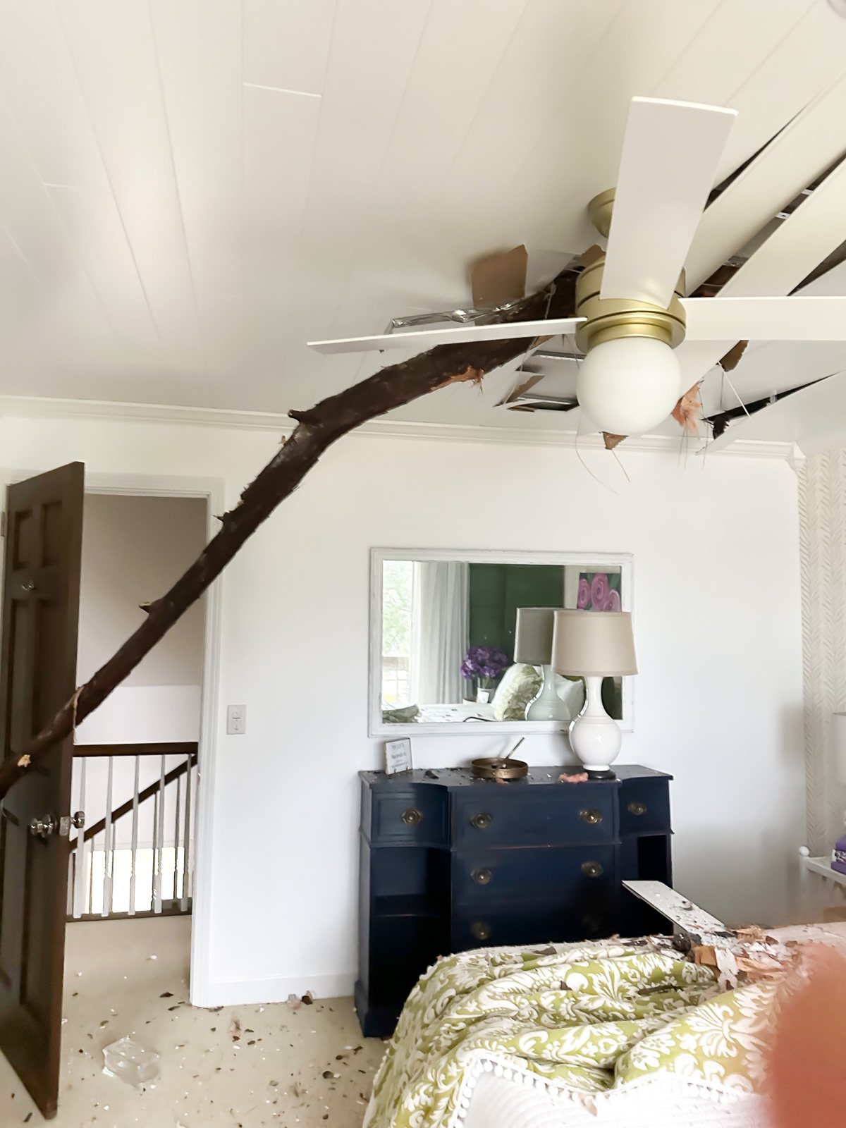 Bedroom in house damage after tree breaks through ceiling.