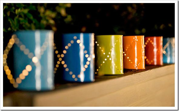 Painted tins can outdoor lights lined up on wall.