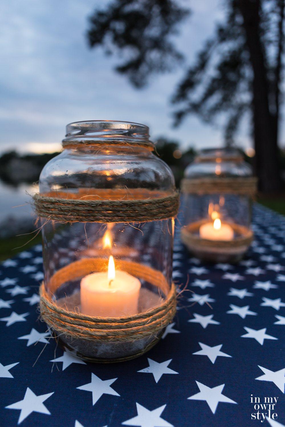 Two DIY glass candle lanterns made nautical style on a white star and navy tablecloth