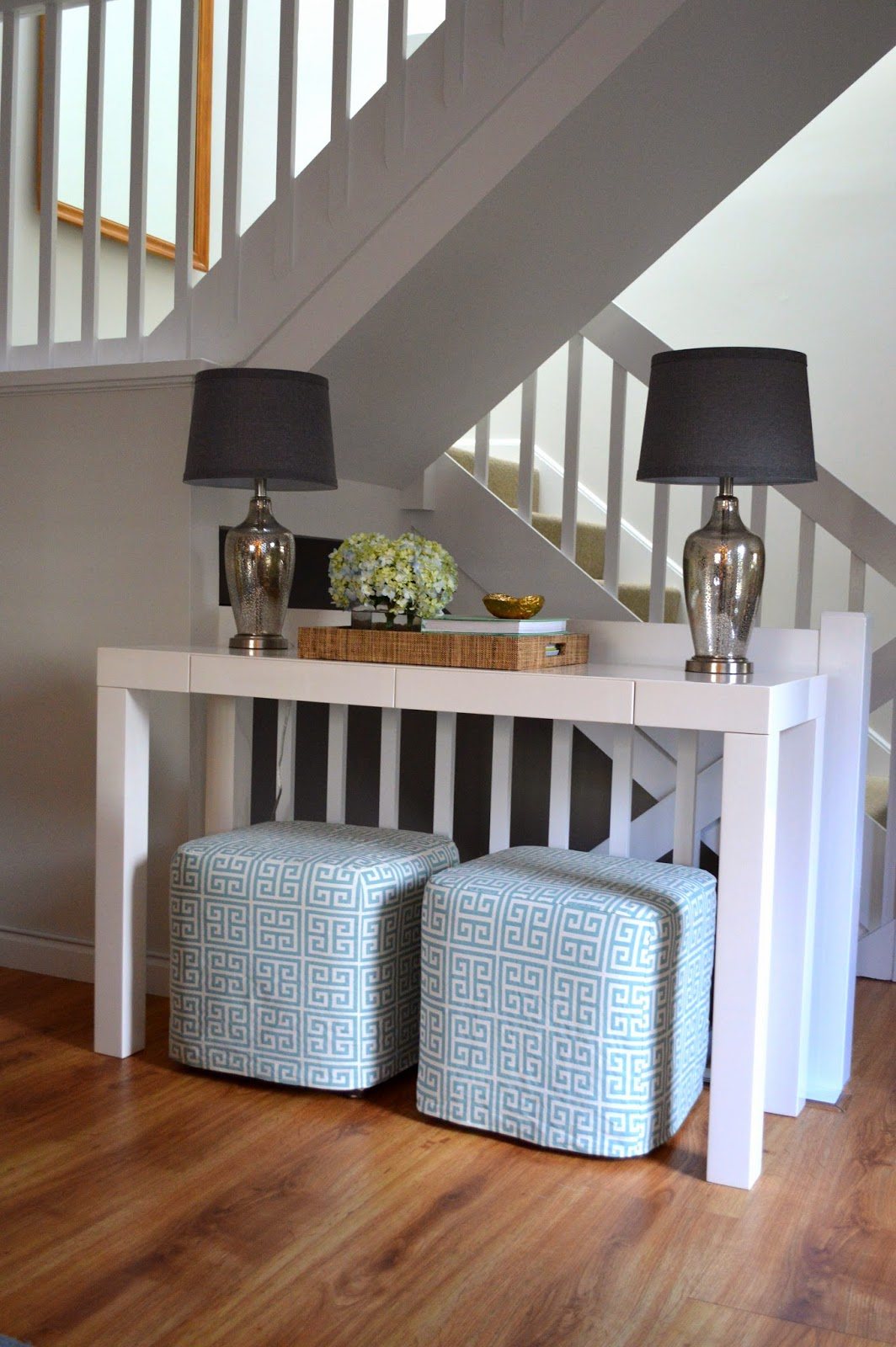 Decorating with ottomans under a foyer console table.