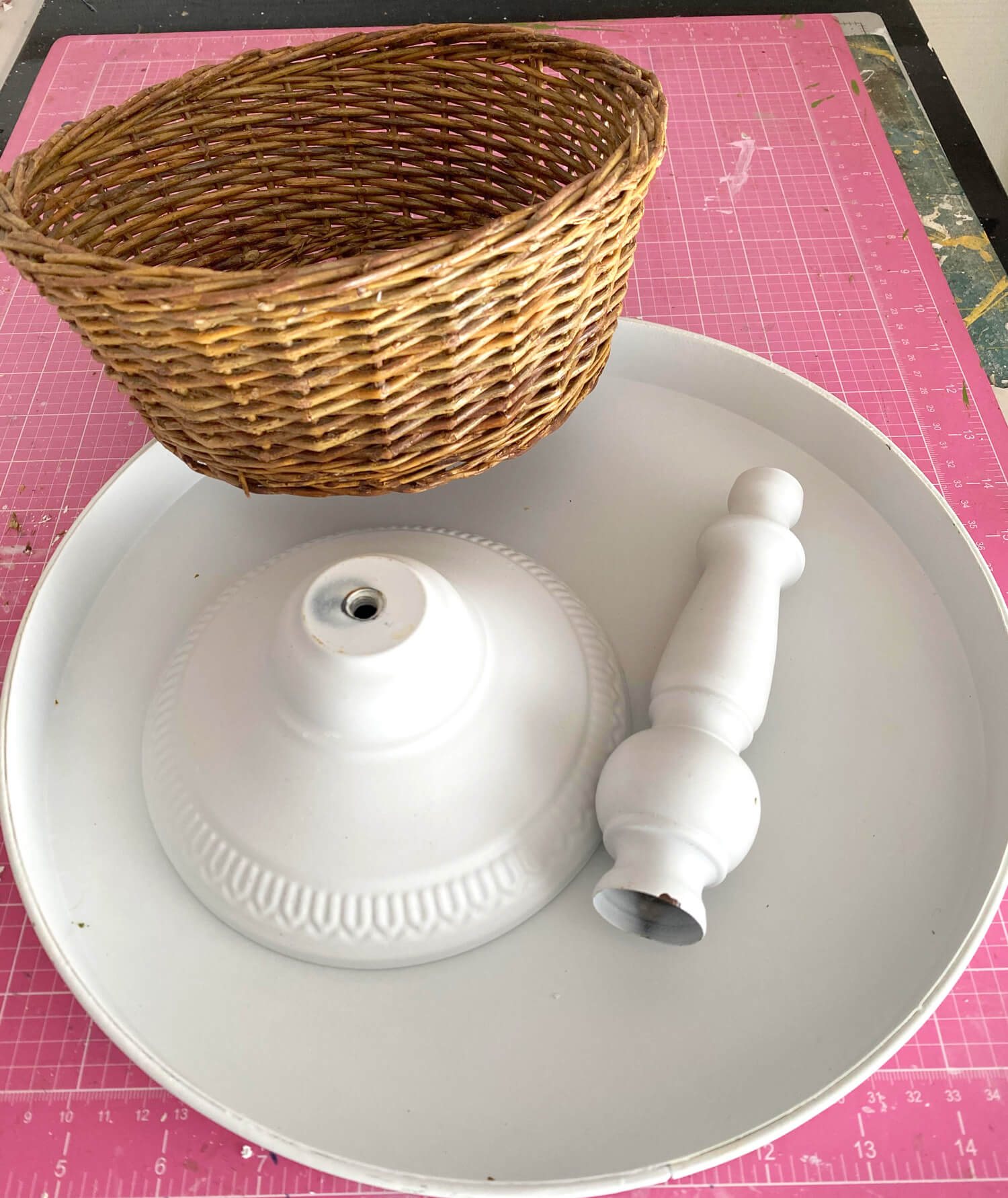 One section of 3 tiered kitchen stand with base, rod and a round wicker basket.