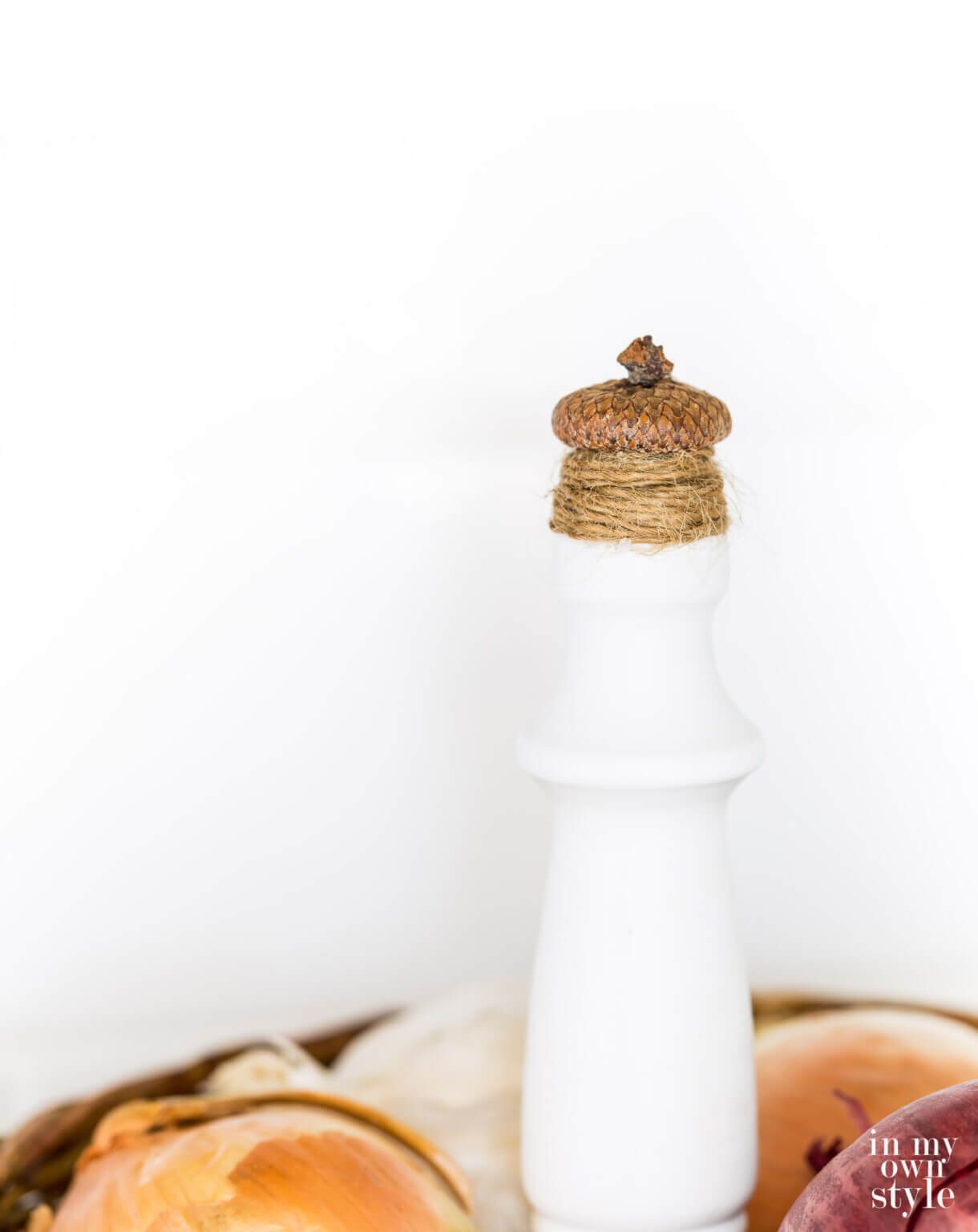 Close up of finished acorn and twine finial on top of a 2 tiered countertop fruit basket.