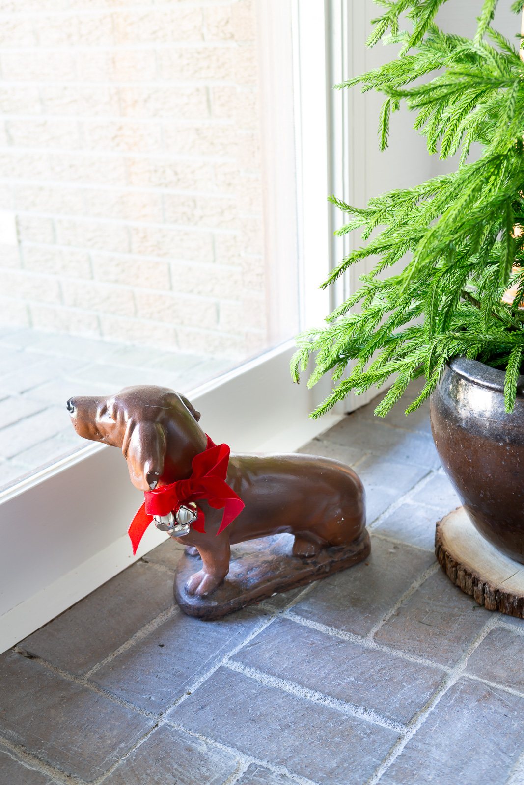 Dog statue with a red bow and jingle bells around his neck.