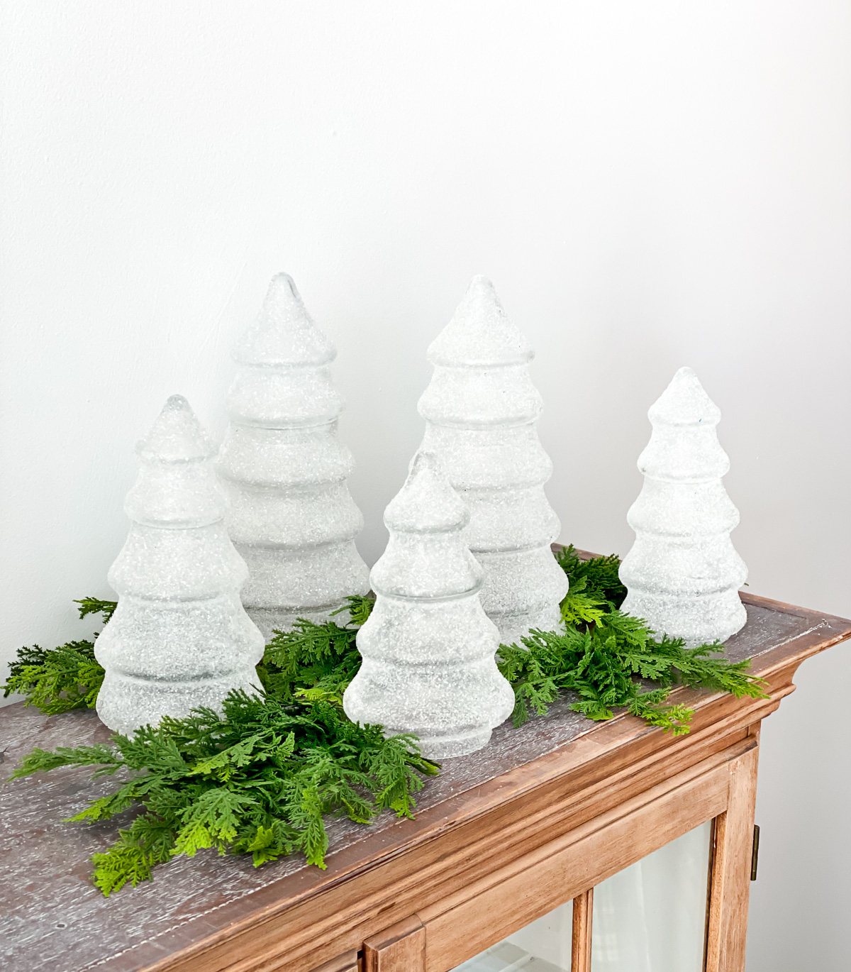 Christmas tree shaped glass jars displayed on a buffet