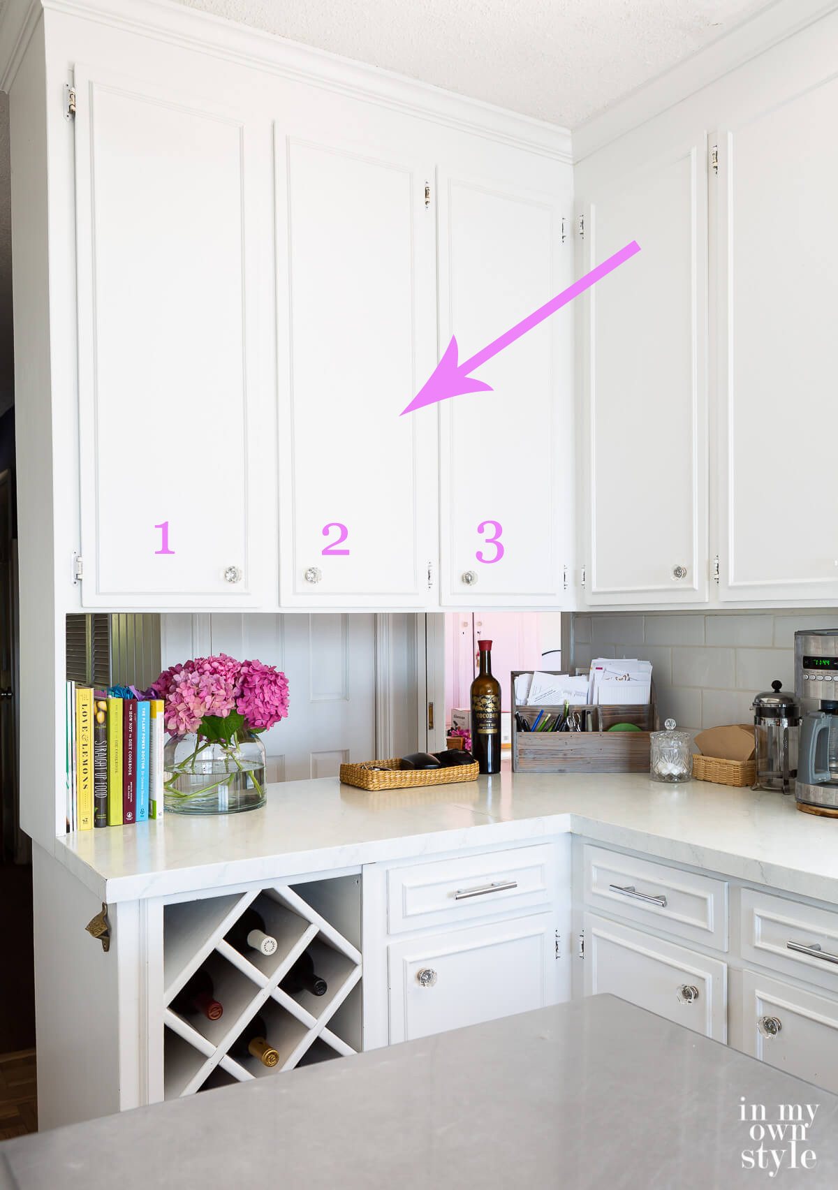 arrow pointing to 3 upper wall cabinets in a small kitchen that are going to be removed.