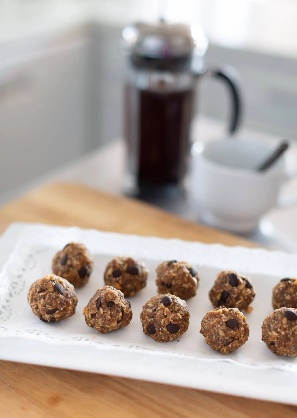 Protein no bake energy balls on a white tray. French coffee press in the background.