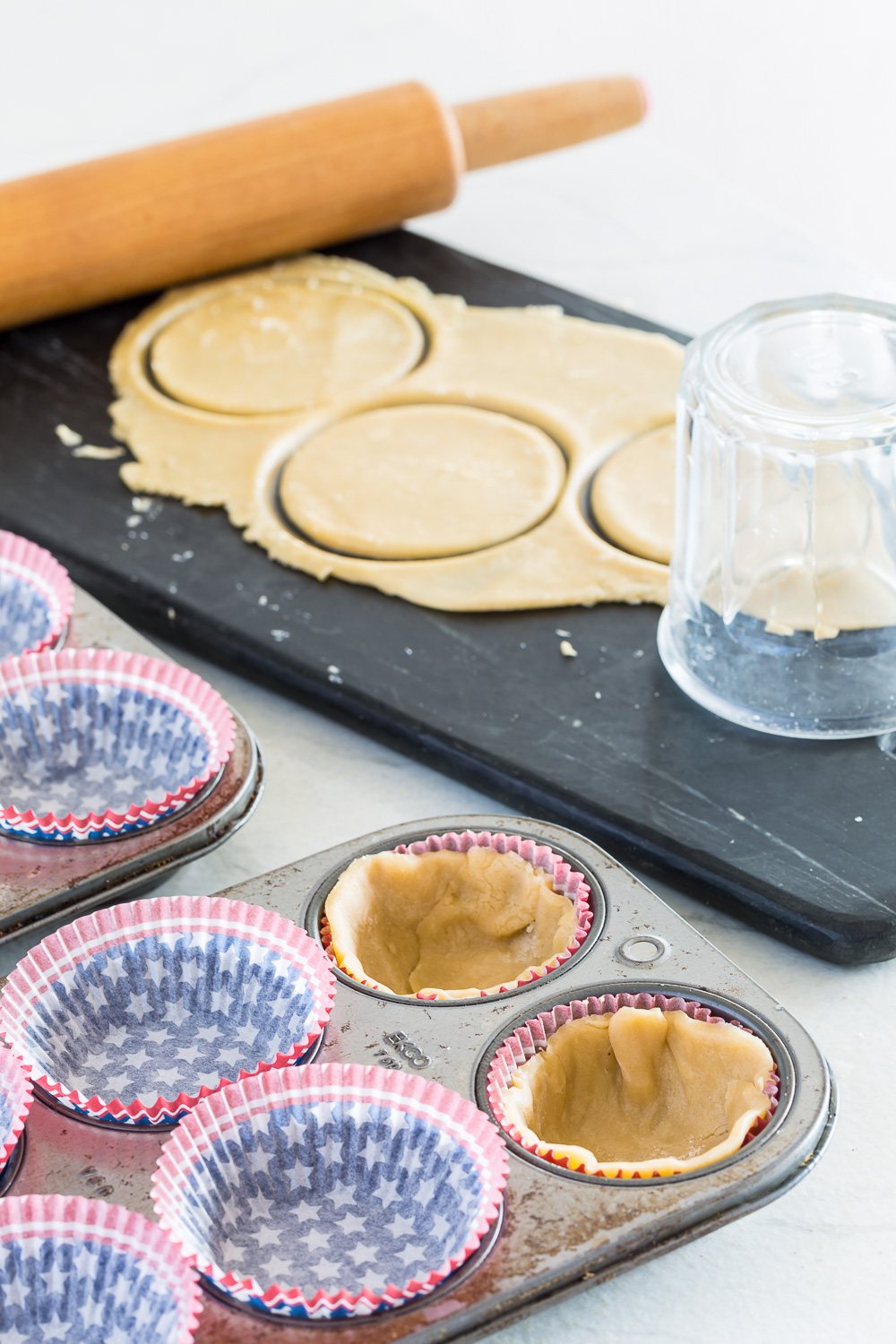 Baking supplies needed to make cupcakes from a frozen pie recipe. Upside down glass is used to make circle cut shapes in rolled dough.