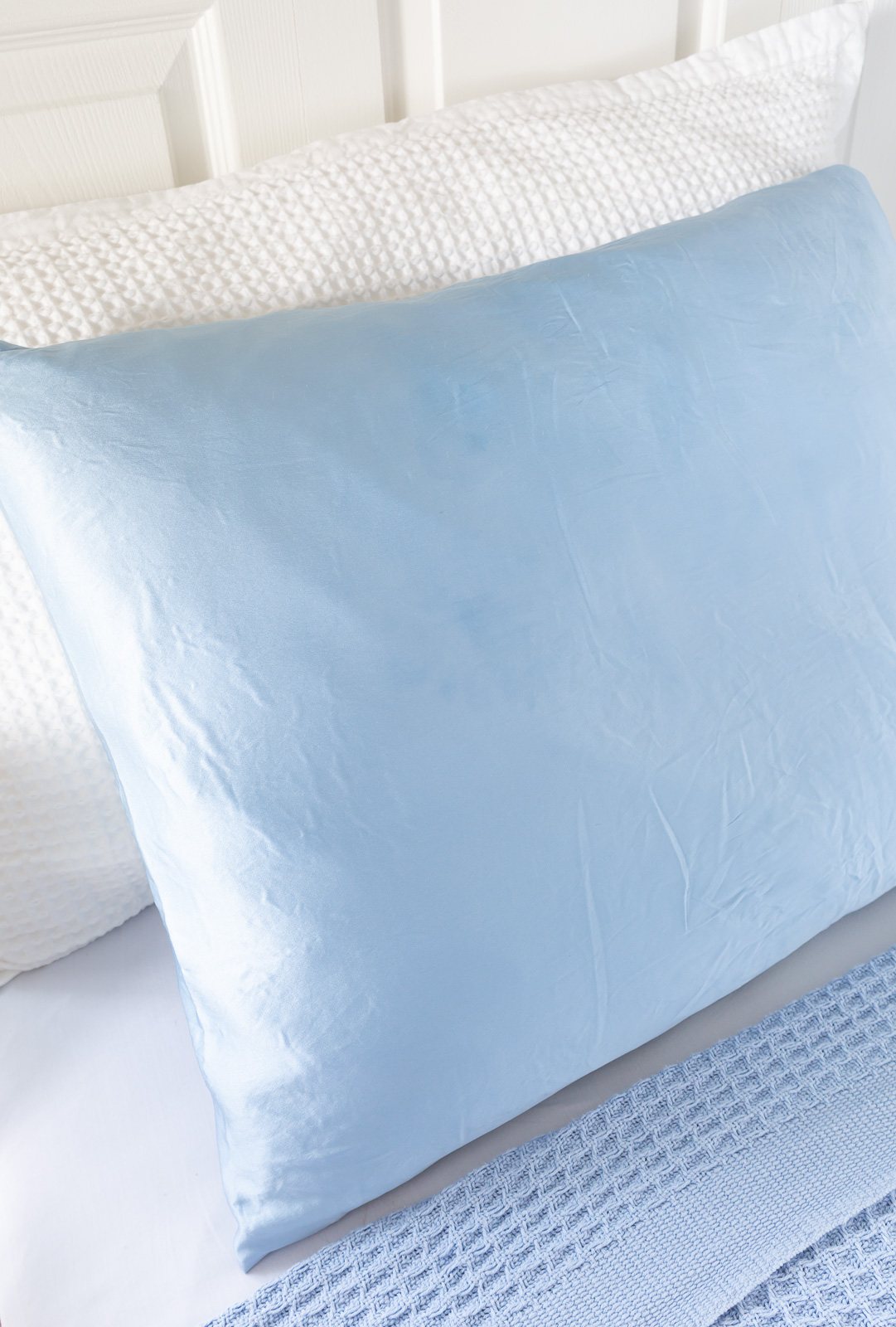 Light blue silk pillowcase on a bed.