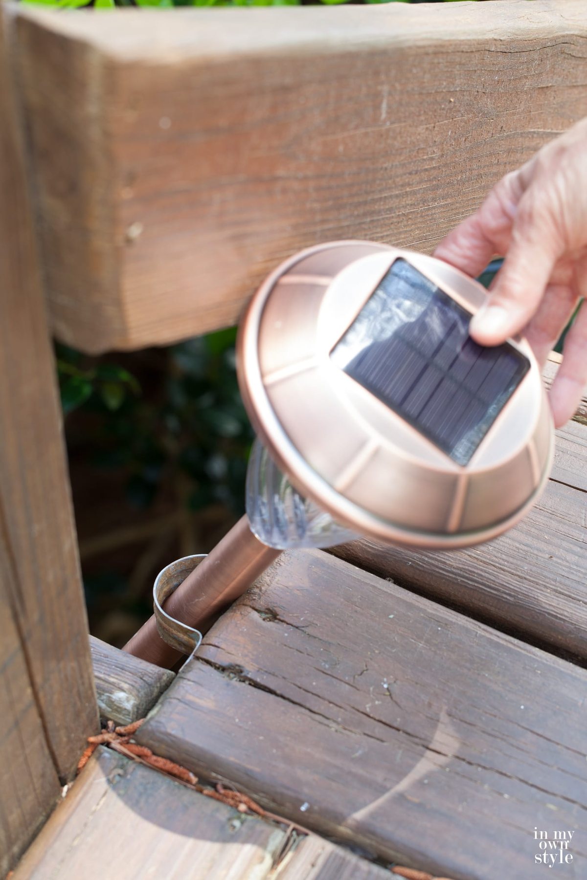 Placing a copper staked solar light in pole bracket along step.