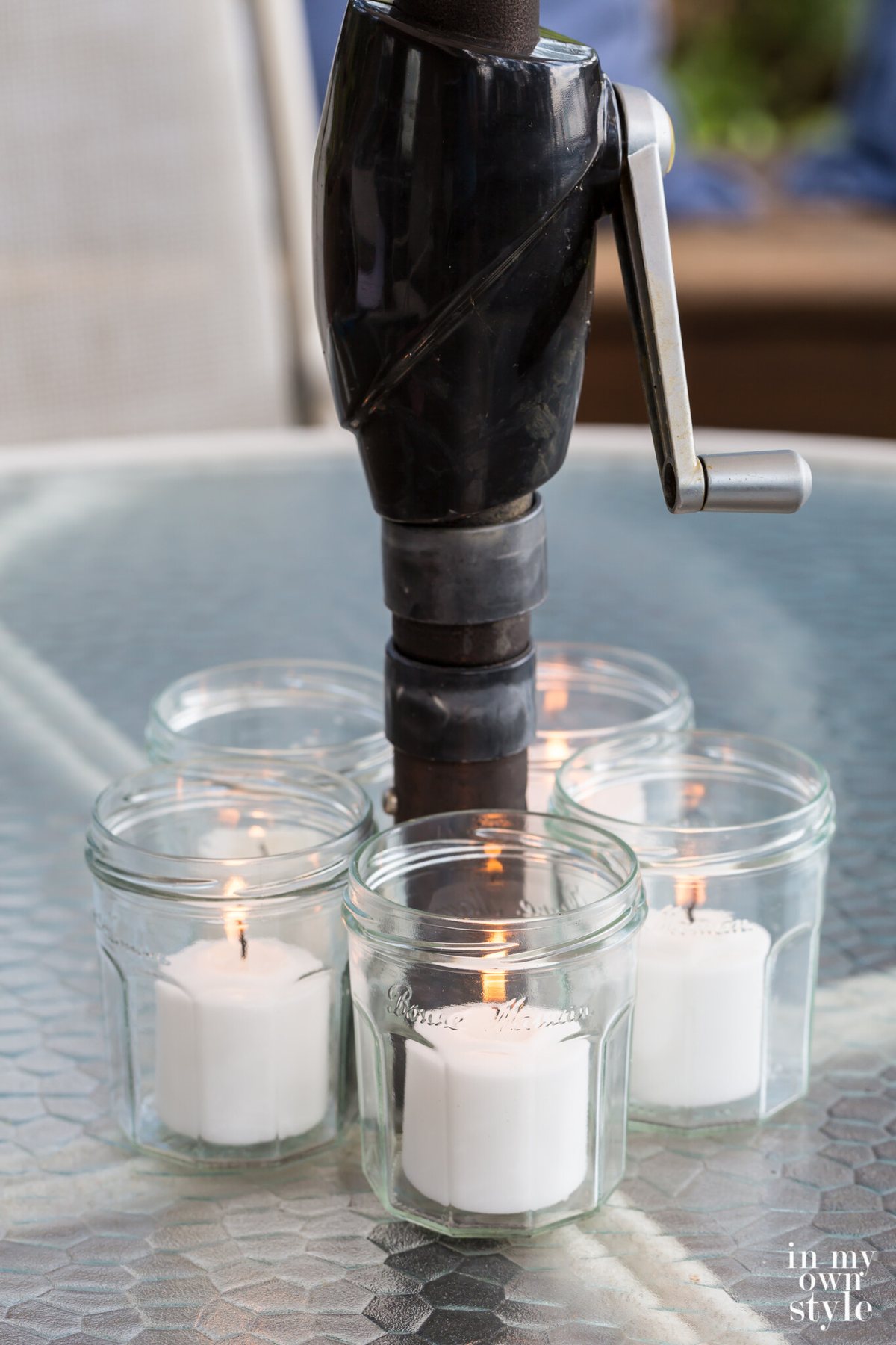 5 jelly jars turned into pretty votive candle holders around a patio tables umbrella pole.