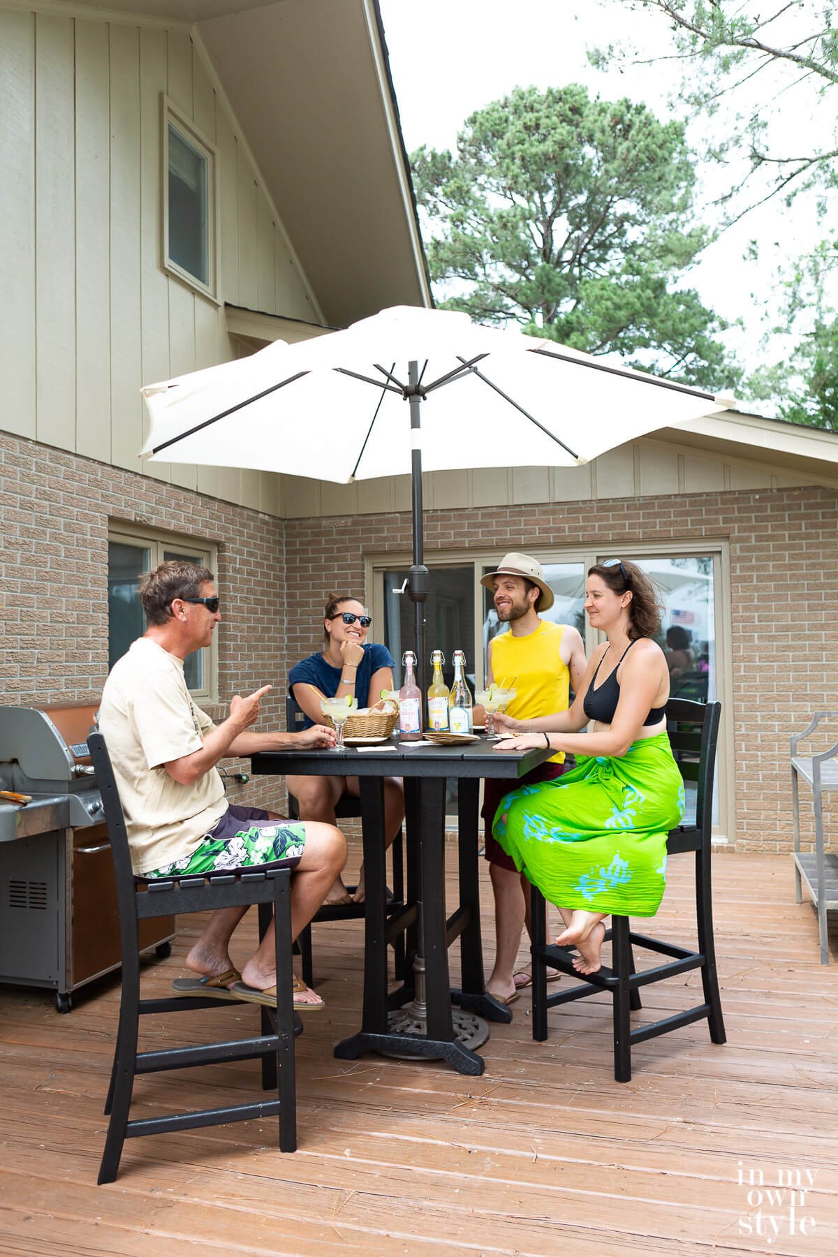 POLYWOOD 5-piece La Casa Cafe Farmhouse Trestle Bar Set Table and chairs with people sitting around it with drinks in hand.