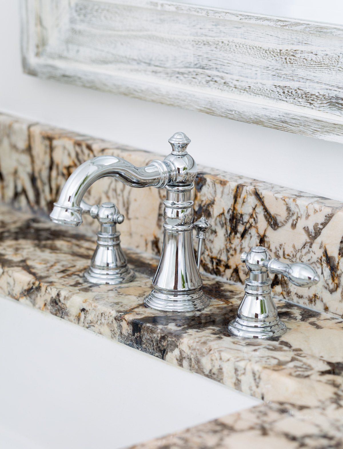 polished chrome bathroom faucet installed on granite sink vanity.
