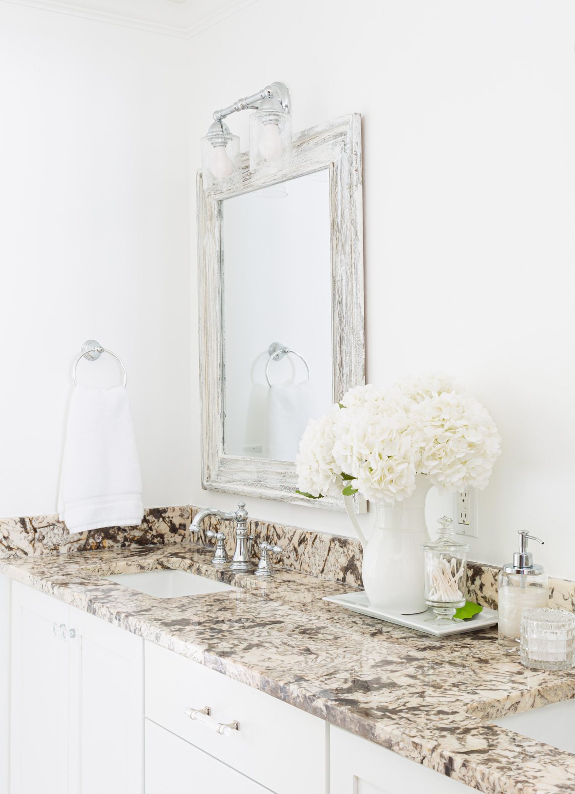 white flowers in white tray on bathroom sink vanity counter.