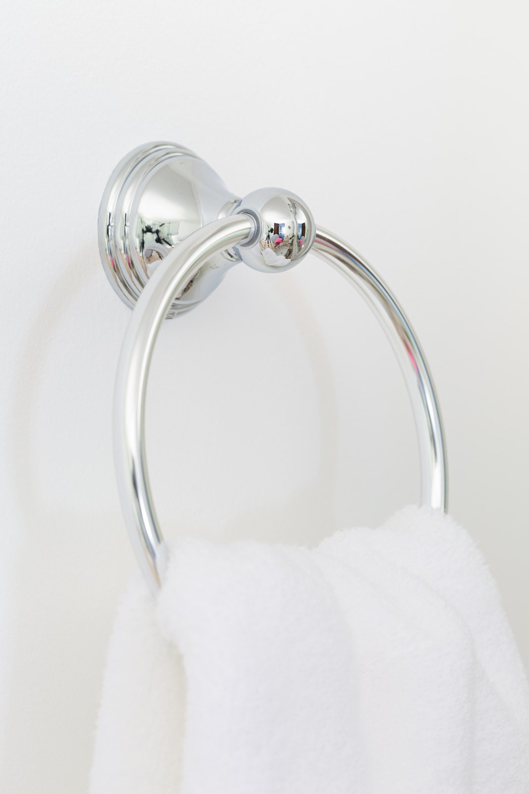 polished chrome towel ring on white wall.