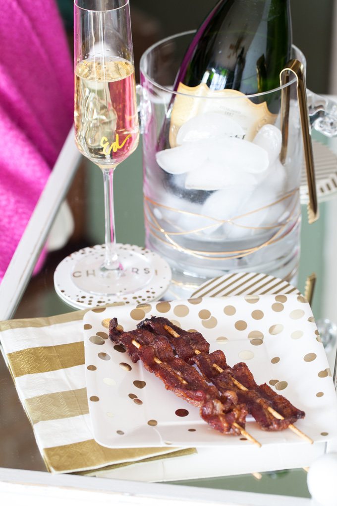 Bacon skewers in gold and white party plate.