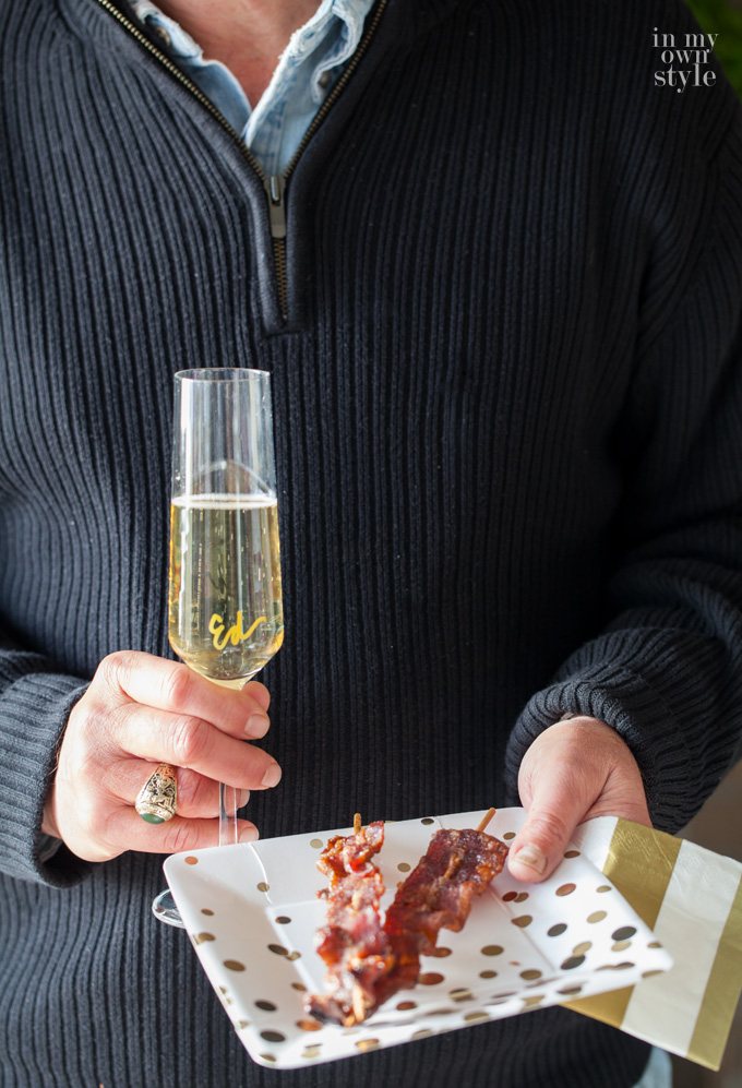 Man holding plate of Spiced Bacon Skewers at a New Year's party
