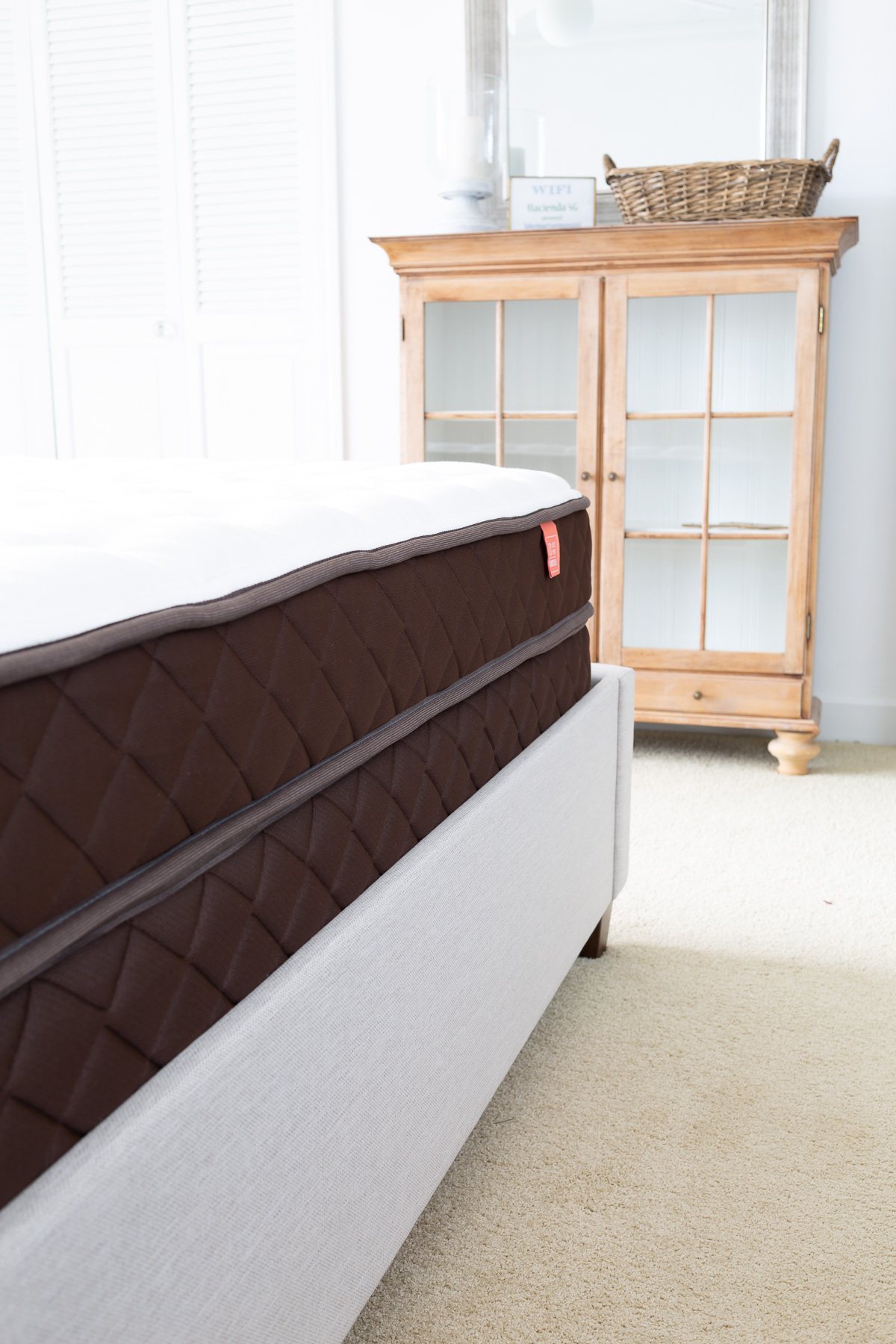 side view of a Christeli Charleston 14.5 mattress and base in an Eastman upholstered platform bed in a bedroom.