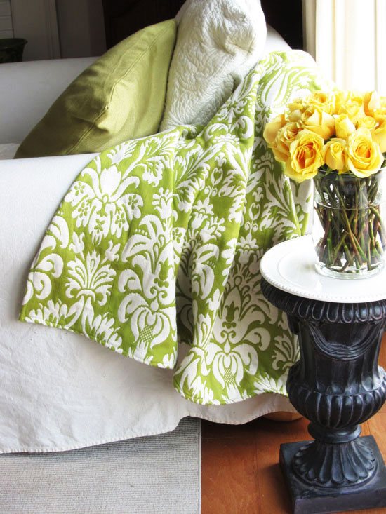 Green and white damask throw blanket on a white sofa