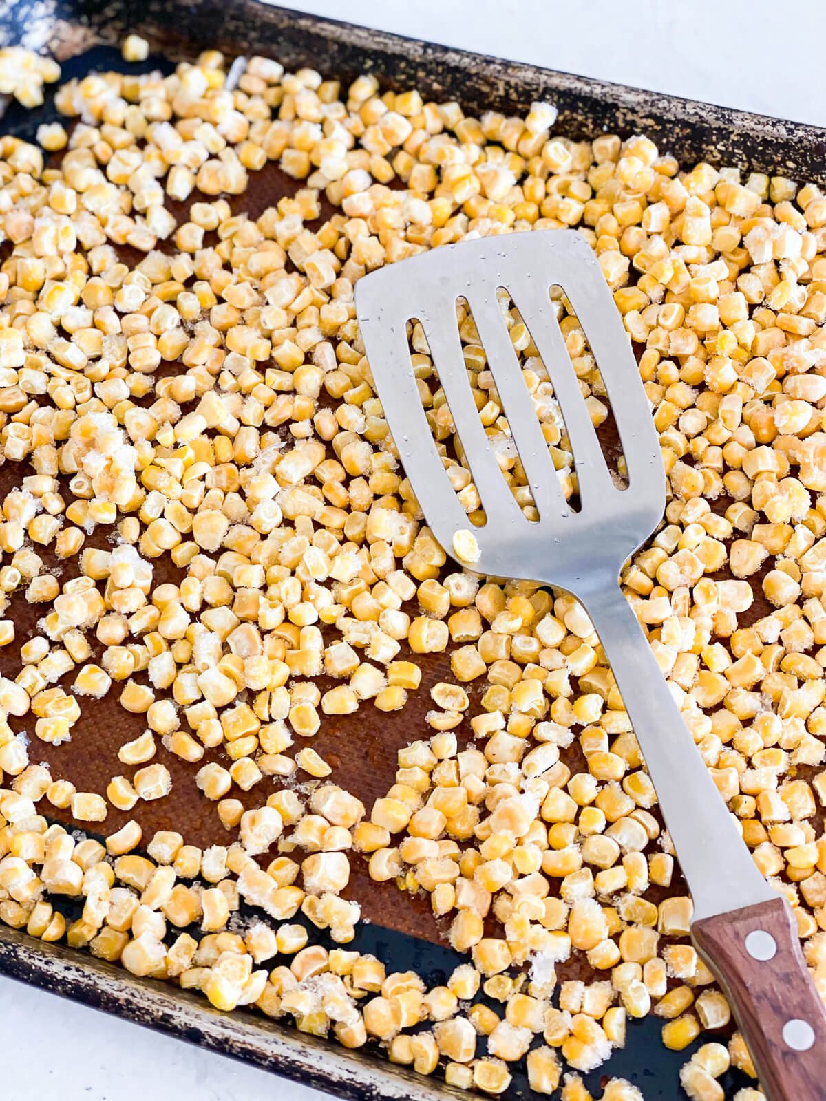 frozen corn kernels being prepared for roasted in an oven.
