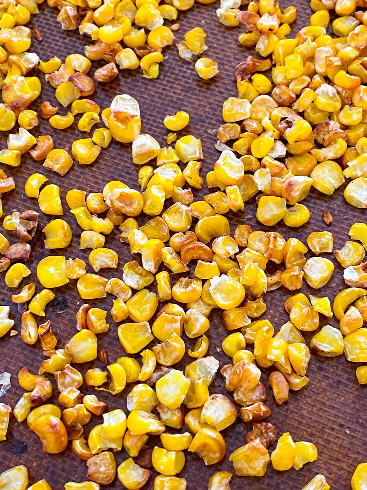 close up of roasted corn kernels on a baking sheet.