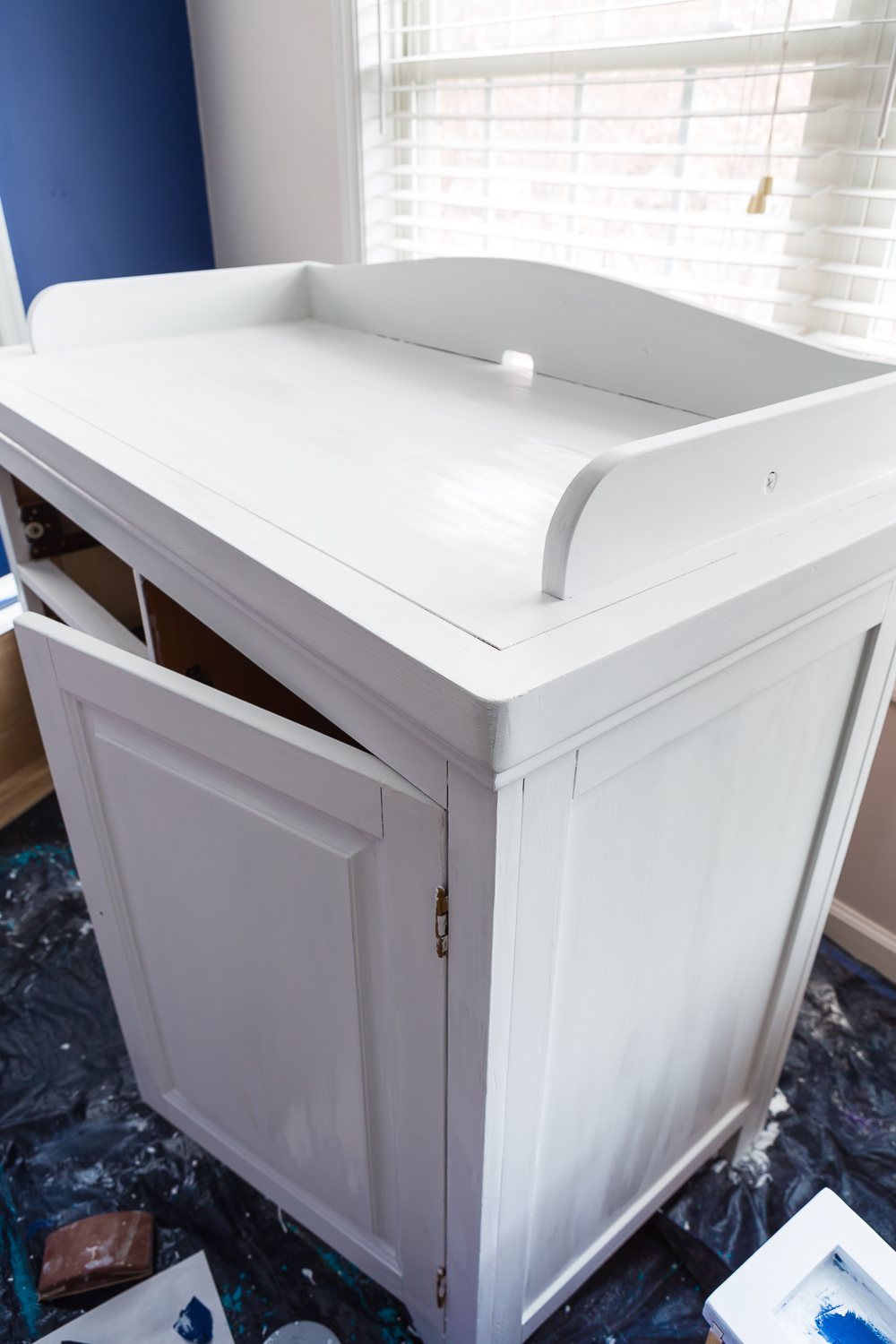second hand furniture makeover of a Baby changing table that is still wet from getting a coat of white paint