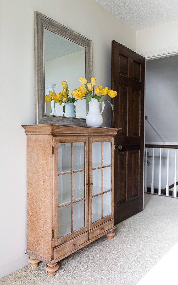 a stripped glass fronted cabinet used as a sideboard