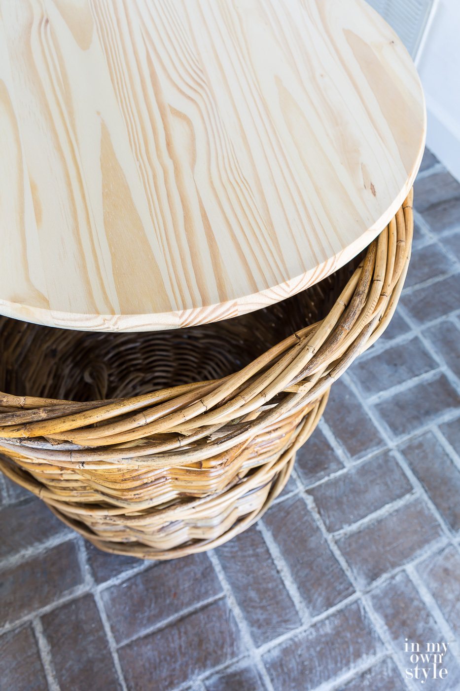 Round wood top on top of large wicker basket.