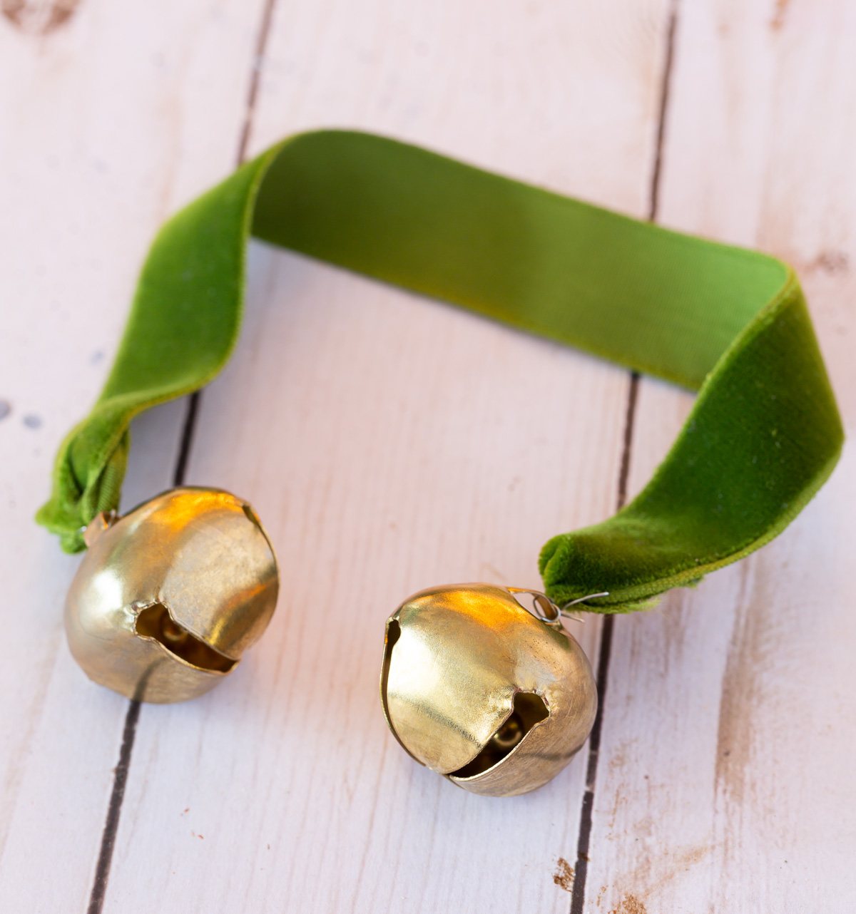 2 gold jingle bells wired to the ends of a piece of green velvet ribbon.
