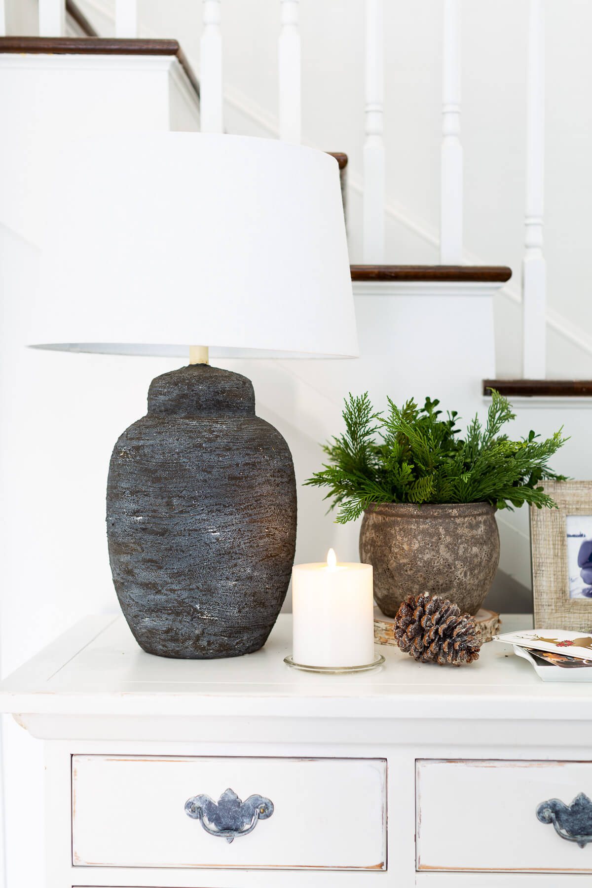 Black based lamp and natural Christmas decor on entryway console table.