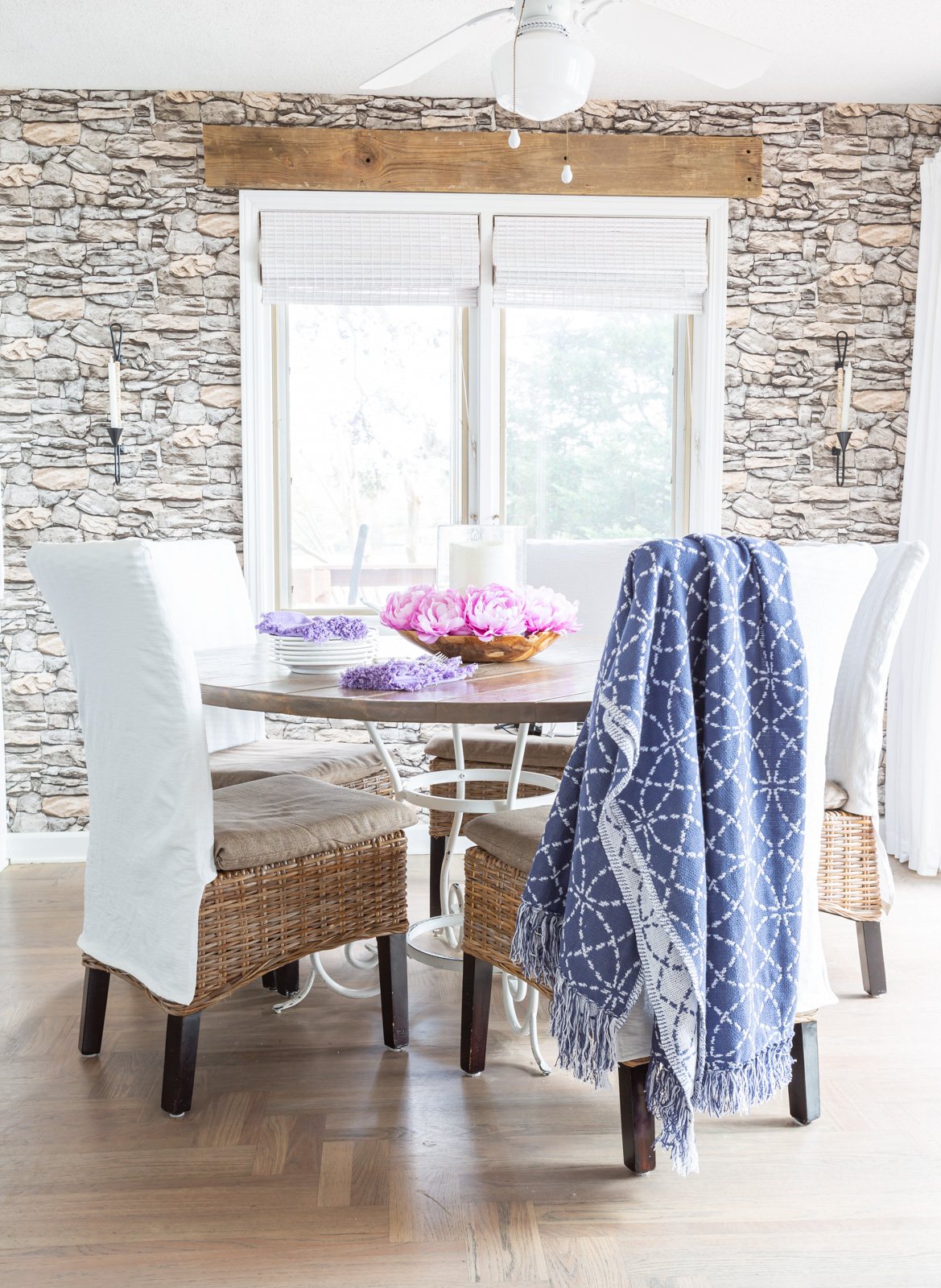 Blue and white throw blanket draped over a white slipcovered kitchen chair around a dining table.