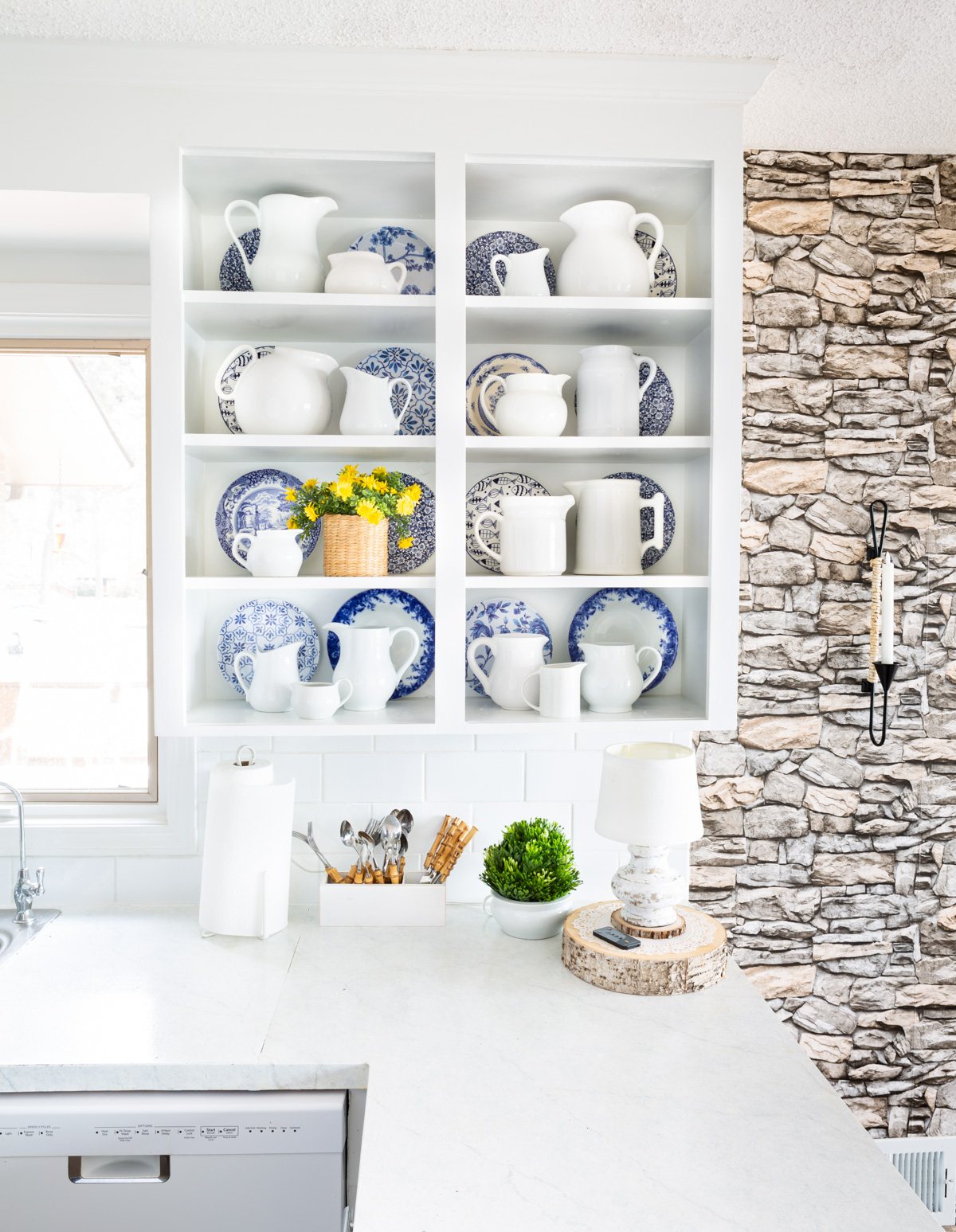 Neutral white kitchen with stone wall and white and blue accent decor.