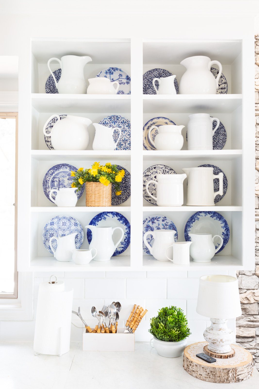 Blue and white decor accents on open shelves in a white kitchen.