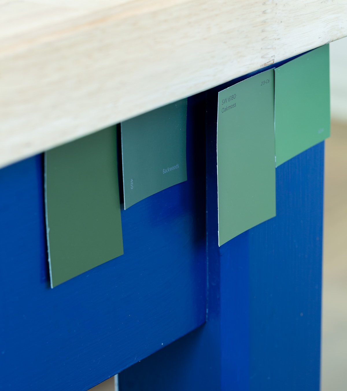 green paint color swatches taped onto a blue island